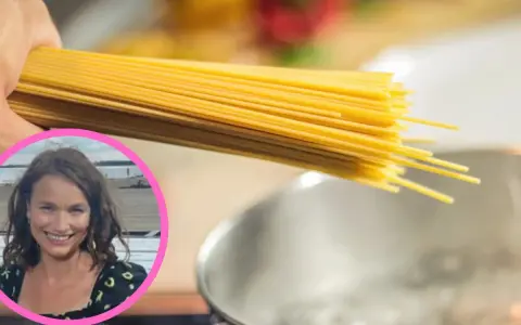 Uczymy się, ile gotować domowy makaron, by był idealny. Kobieta z uśmiechem trzyma pęczek spaghetti nad gotującą się wodą.