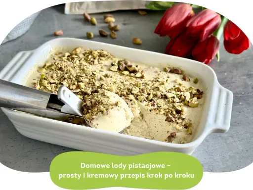 Kremowe lody pistacjowe w białej formie, posypane orzechami. Łyżka właśnie nabiera porcję tego pysznego deseru.
