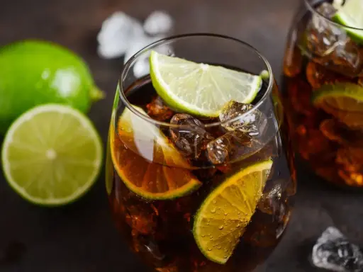 Orzeźwiający Cuba Libre z kostkami lodu i plasterkami limonki, gotowy do wypicia.