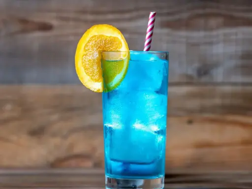 Orzeźwiający drink z blue curacao, ozdobiony plasterkiem pomarańczy i limonki, z kolorową słomką. Idealny na letnie popołudnie.