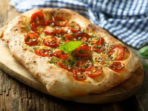 Pyszna focaccia z pomidorkami koktajlowymi i bazylią. Idealna jako przekąska lub dodatek do dania. Z czym jeść? Z sałatką, dipem lub solo!