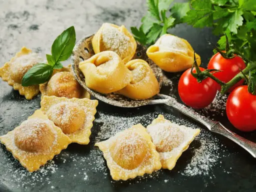 Świeże ravioli i tortellini, posypane cukrem pudrem, z pomidorkami koktajlowymi i bazylią. Idealne z czym podawać ravioli? Z prostym sosem!