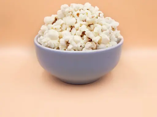 Pyszny, puszysty popcorn w niebieskiej misce. Idealny, gdy zastanawiasz się, jak zrobić popcorn na wieczór filmowy.