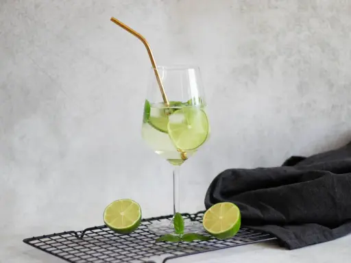 Orzeźwiający drink Hugo z limonką i miętą, idealne proporcje na lato. Złota słomka dodaje elegancji.