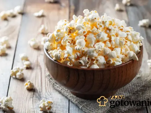 Pyszny popcorn w drewnianej misce, rozsypany na stole. Czy da się zrobić popcorn w piekarniku? Tak, i wygląda równie apetycznie!