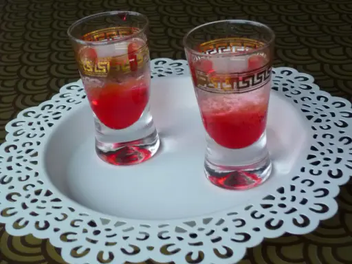 Dwa kieliszki z czerwonym drinkiem, ozdobione złotym wzorem. Wyglądają jakby miały moc, niczym wściekły pies drink.