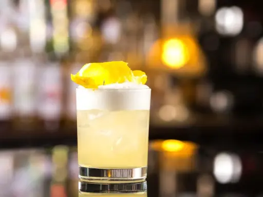 Klasyczny whisky sour z pianką i skórką cytryny, idealny na wieczór.