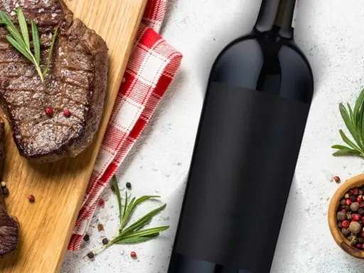 Idealne jakie wino do steka? Soczyste steki na desce, butelka czerwonego wina i przyprawy.