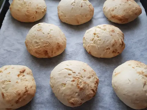 Świeżo upieczone bułki bez drożdży, lekko zarumienione, ułożone na papierze do pieczenia.