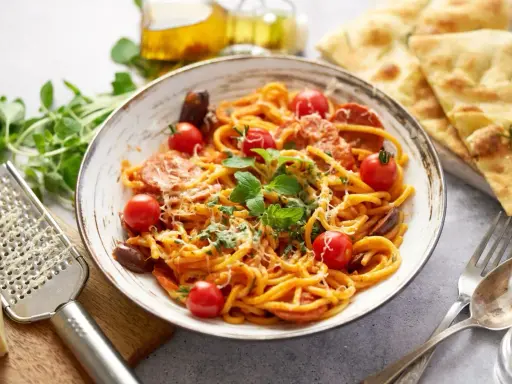 Pyszny makaron z chorizo, pomidorkami koktajlowymi i świeżą bazylią, posypany parmezanem. Idealny na szybki obiad.