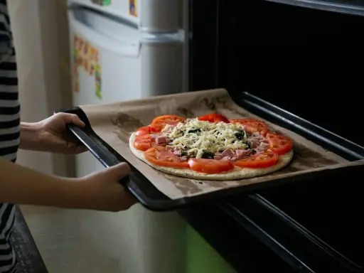 Wkładanie pizzy do piekarnika. Dzięki termoobiegowi ciasto będzie chrupiące, a ser idealnie roztopiony.