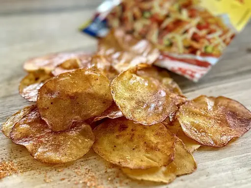 Chrupiące chipsy z piekarnika, lekko przypieczone, z widocznym opakowaniem w tle. Idealna przekąska!