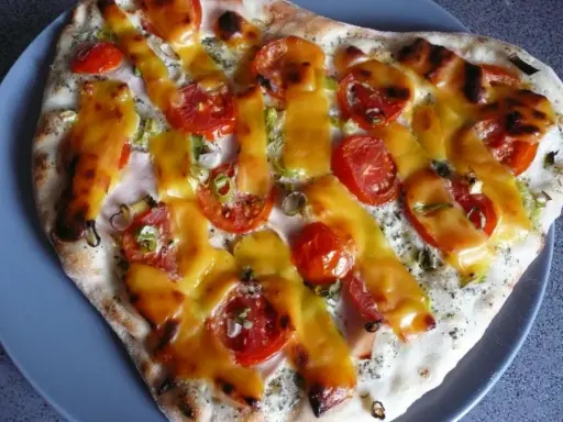 Pizza z pomidorami i serem, polana sosem śmietanowym.