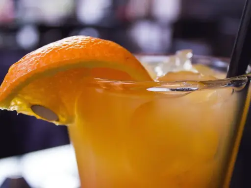 Orzeźwiający drink z suchym lodem, ozdobiony plasterkiem pomarańczy. Dymiący napój wygląda magicznie.