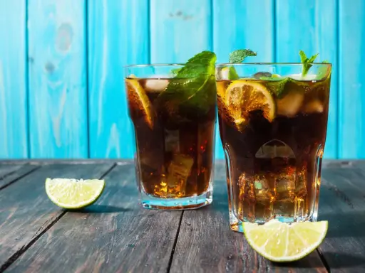 Dwa orzeźwiające drinki z rumem, lodem, miętą i limonką na drewnianym blacie.