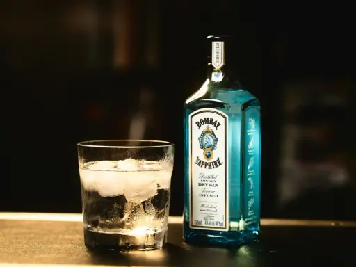 Szklanka z lodem i butelka Bombay Sapphire gin. Idealny składnik na orzeźwiający bombay sapphire drink.