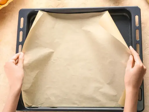 Ręce układają papier do pieczenia na blasze. To świetny sposób, by nic nie przywarło!