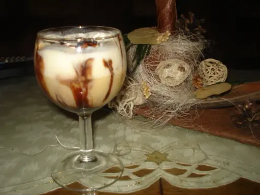 Pyszny drink z adwokatem, udekorowany czekoladą, na tle świątecznych ozdób.