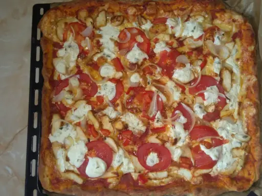 Pyszna, prostokątna pizza bez drożdży z kurczakiem, pomidorami, cebulą i serem.