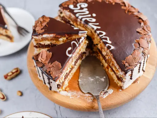 Pyszne snickers ciasto z czekoladą i orzeszkami, pokrojone na kawałki, gotowe do podania.