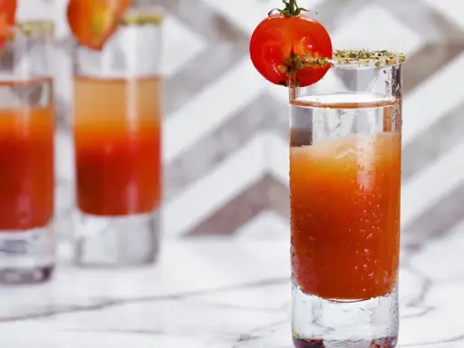 Trzy shoty z drinkiem, który wygląda jak przepis na to, jak zrobić wściekłego psa. Każdy ozdobiony pomidorkiem koktajlowym.