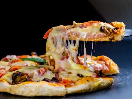 Rozciągający się ser z kawałka pysznej pizzy z kurczakiem, pomidorami i grzybami.