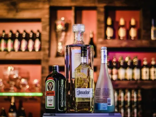 Jägermeister z sokiem jabłkowym i innymi alkoholami na barze.