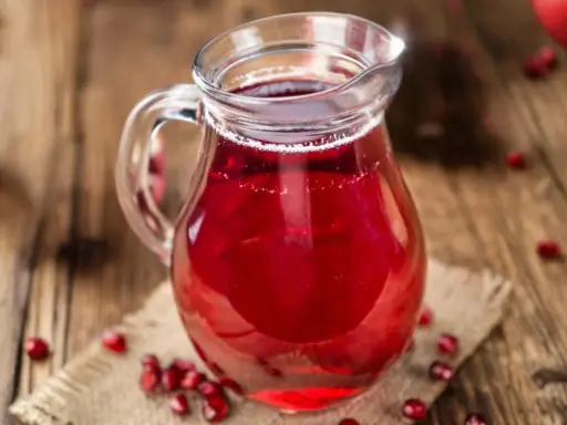 Szklany dzbanek z sokiem z granatu, otoczony owocami. Idealny do drinków, deserów, a także jako baza do sosów. Sok z granatu z czym łączyć?
