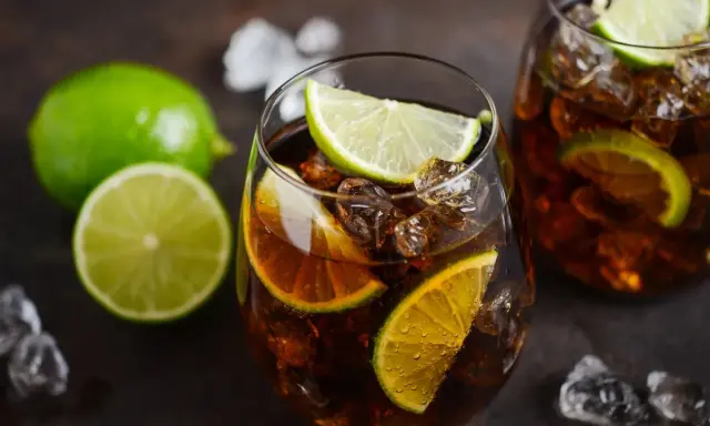 Orzeźwiający Cuba Libre z kostkami lodu i plasterkami limonki, gotowy do wypicia.