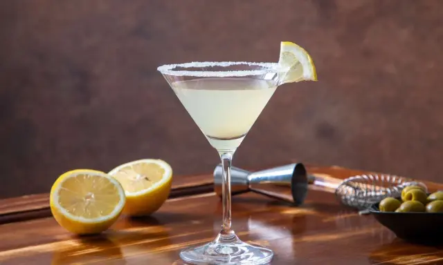Orzeźwiające drinki z martini bianco, ozdobione cytryną i solą, obok świeżych cytryn i oliwek.
