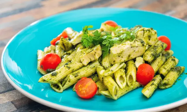Penne z kurczakiem i pomidorkami koktajlowymi w sosie pesto, z dodatkiem mozzarelli.