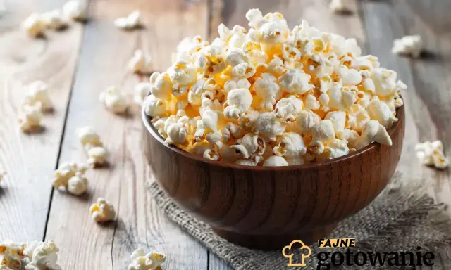 Pyszny popcorn w drewnianej misce, rozsypany na stole. Czy da się zrobić popcorn w piekarniku? Tak, i wygląda równie apetycznie!