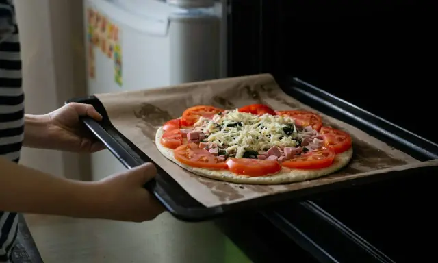 Wkładanie pizzy do piekarnika. Dzięki termoobiegowi ciasto będzie chrupiące, a ser idealnie roztopiony.