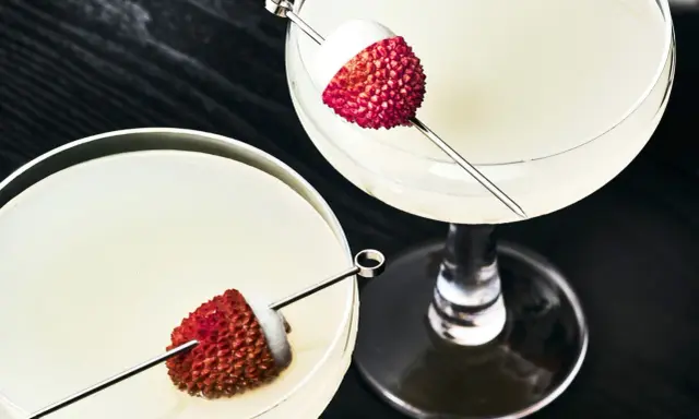 Dwa eleganckie drinki z liczi, ozdobione owocami na patyczkach, kuszą swoim orzeźwiającym wyglądem.
