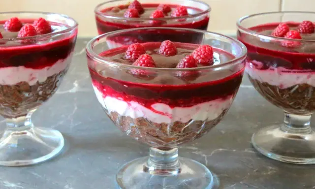 Mini deserki z mascarpone, przełożone warstwą musu i malinową galaretką, ozdobione świeżymi malinami.