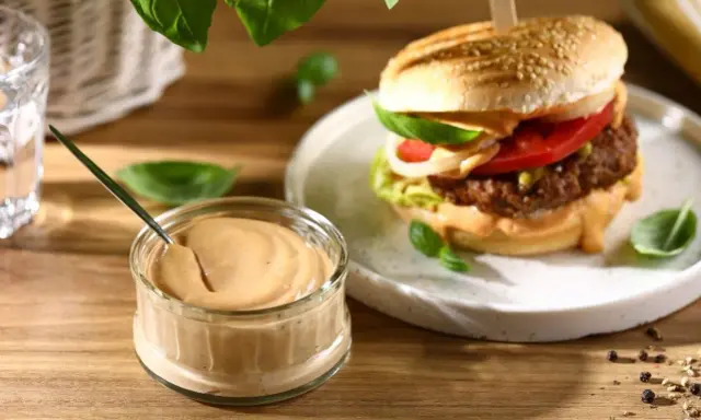 Pyszny sos do burgera w słoiczku, obok apetycznego burgera z dodatkami. Idealny do każdej kanapki.