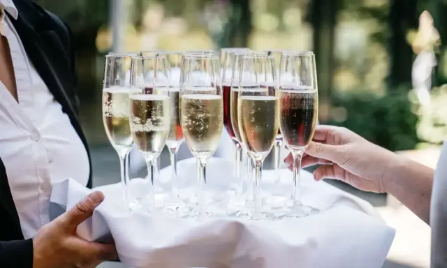 Taca z kieliszkami musującego wina, idealna do drinków typu Hugo. Zastanawiasz się, jakie prosecco do Hugo wybrać?
