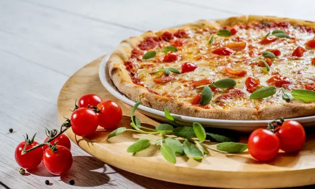 Pyszna pizza z pomidorkami i szałwią. Idealne jakie przyprawy do pizzy? Świeże zioła i pieprz.
