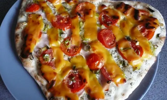 Pizza z pomidorami i serem, polana sosem śmietanowym.