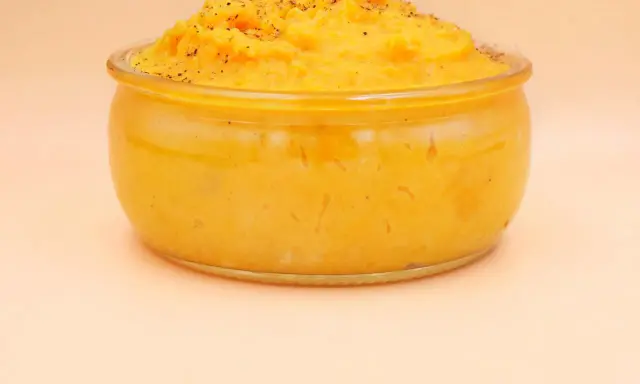 Pomarańczowe puree z batatów w szklanym naczyniu, posypane pieprzem.