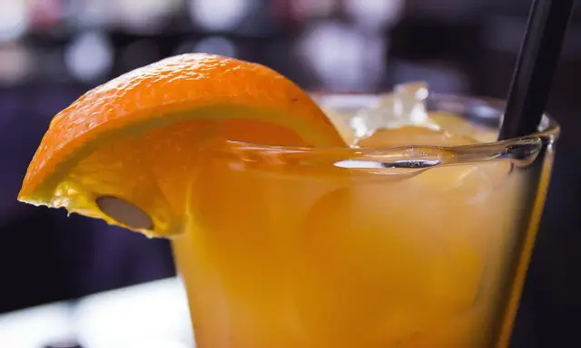 Orzeźwiający drink z suchym lodem, ozdobiony plasterkiem pomarańczy. Dymiący napój wygląda magicznie.