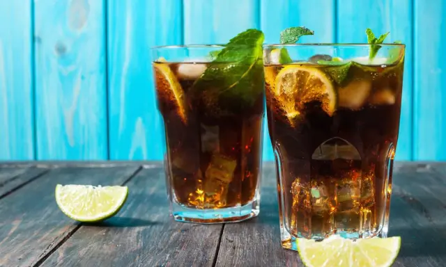 Dwa orzeźwiające drinki z rumem, lodem, miętą i limonką na drewnianym blacie.
