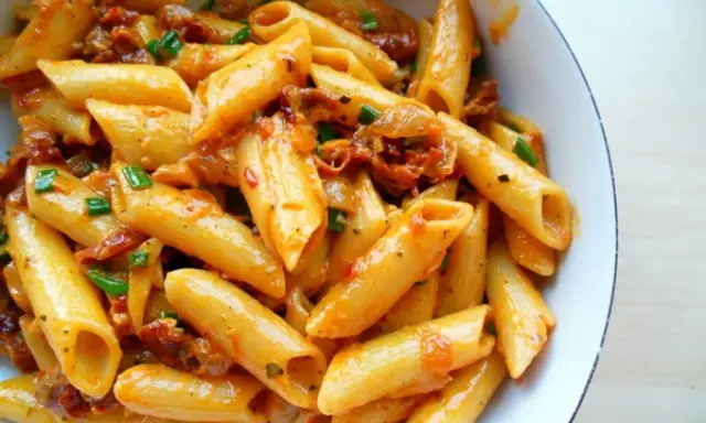 Penne z sosem z suszonych pomidorów i zieloną cebulką, apetyczne danie pełne smaku.