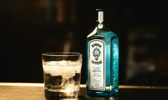 Szklanka z lodem i butelka Bombay Sapphire gin. Idealny składnik na orzeźwiający bombay sapphire drink.