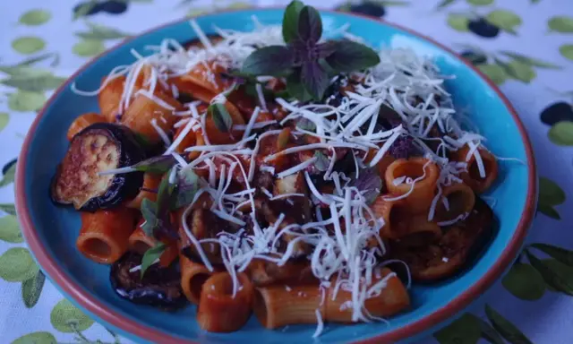 Rigatoni alla norma z bakłażanem, pomidorami i bazylią, posypane startym serem.
