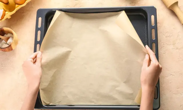 Ręce układają papier do pieczenia na blasze. To świetny sposób, by nic nie przywarło!