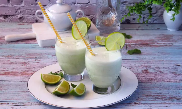 Dwa orzeźwiające drinki z mlekiem skondensowanym, ozdobione plasterkami limonki i miętą, na talerzu.