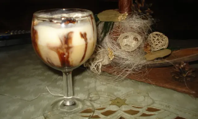 Pyszny drink z adwokatem, udekorowany czekoladą, na tle świątecznych ozdób.
