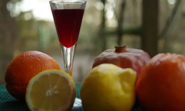 Szklanka z czerwonym napojem, obok pomarańcze, cytryna i granat. Czy to grenadyna? Hajduczek naturalnie.