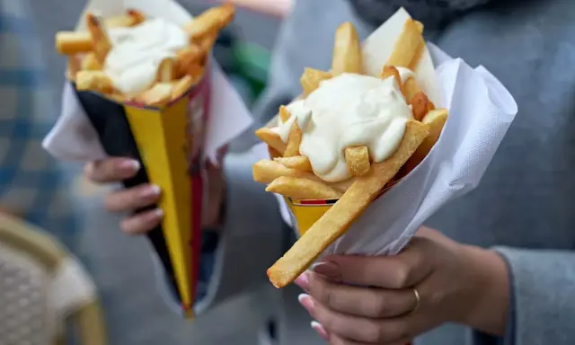 Dwie porcje chrupiących frytek w rożkach, polane obficie kremowymi sosami. Idealne na szybką przekąskę!